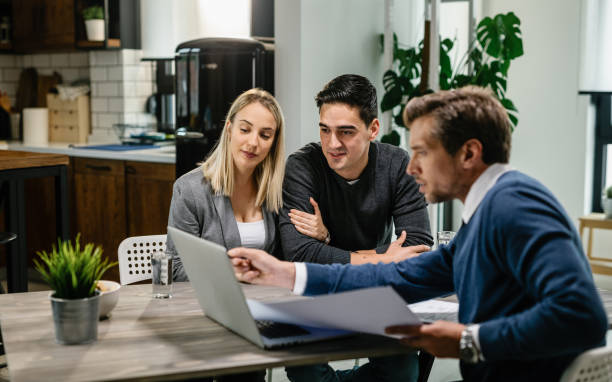 istock Smiling couple using a computer with their investment agent on a meeting. 1157133749
