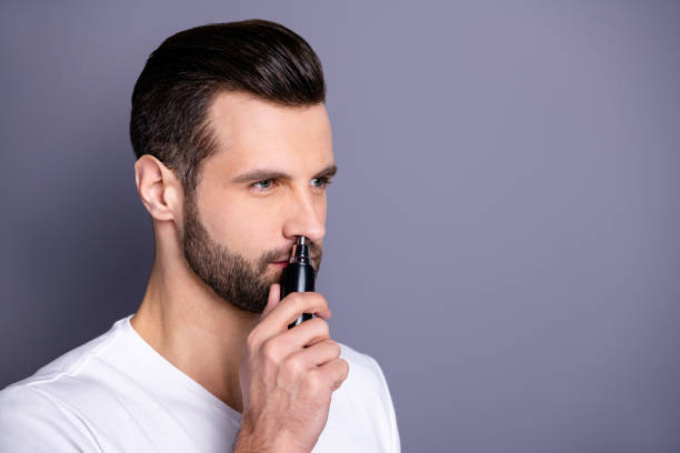 de cerca lado perfil foto increíble él su proceso sin pelo macho comprar comprador nueva novedad de la mano listo quitar el pelo de la oreja de la nariz con ayuda cómoda recortador usar casual camiseta blanca aislada fondo gris - picking nose fotografías e imágenes de stock