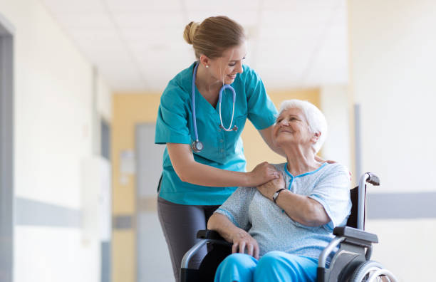 senior woman in wheelchair with nurse in hospital - senior adult hospital uniform gray hair imagens e fotografias de stock