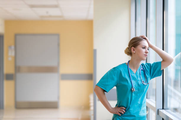 infermiera stanca nel corridoio dell'ospedale - doctor emotional stress worried healthcare and medicine foto e immagini stock