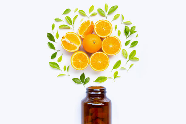 istock Vitamin C bottle and pills with orange fruit on white 1157136289