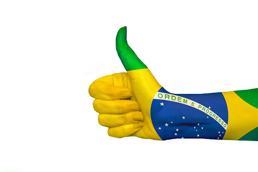 Hand showing the sign of like and okay. Close up of female hand showing victory sign isolated on white background. Woman hand gesturing peace sign. Brazil flag painted on hand showing thumbs up in isolated background