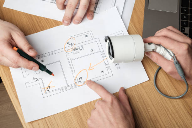 istock Two people discussing CCTV project. Video security equipment and blueprint on a table 1157139040