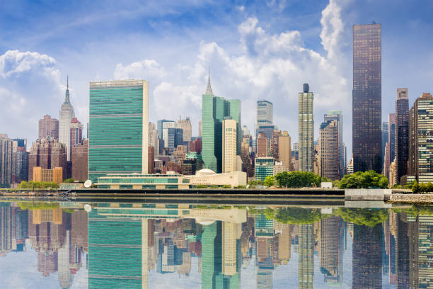 new york city skyline with midtown manhattan skyscrapers, un building and empire state building reflected in water of east river, ny, usa. - manhattan new york city skyline east river imagens e fotografias de stock