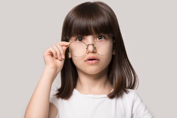 lustiges kleines mädchen senken brille, die auf die kamera schaut, fühlen staunen - child bizarre little girls humor stock-fotos und bilder