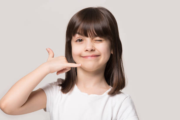 Little funny girl makes call me hand gesture studio shot