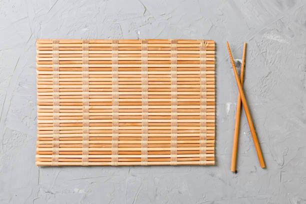 istock two sushi chopsticks with empty bamboo mat or wood plate on stone Background Top view with copy stace 1157139779