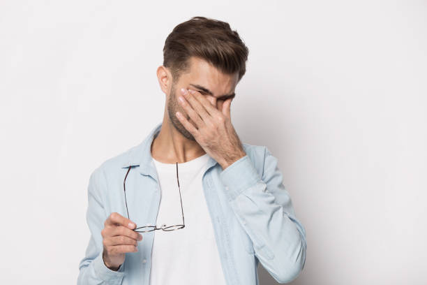Man taking off glasses suffers from dry eyes studio shot