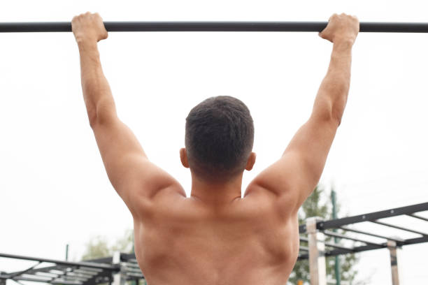 istock Healthy Lifestyle. Young man shirtless exercising outdoors pull-up on bar back view close-up 1157140767