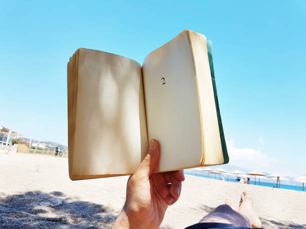 istock young man  lies on the beach reading a book 1157142623