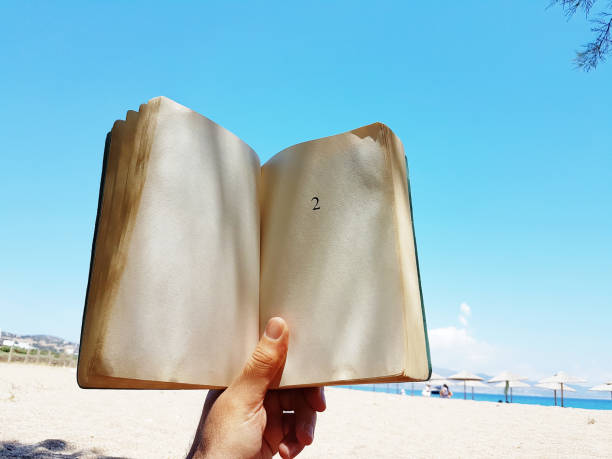 istock young man  lies on the beach reading a book 1157143355