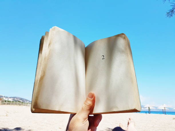 istock young man  lies on the beach reading a book 1157143431
