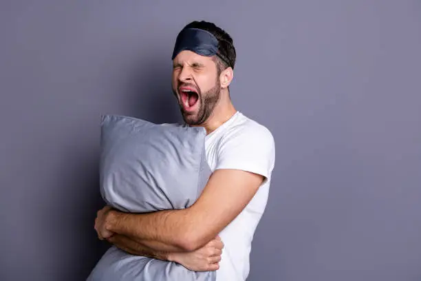 Portrait of his he nice-looking attractive exhausted sleepy bearded guy holding in hands pillow, drowsiness going to bed isolated over gray pastel violet purple background