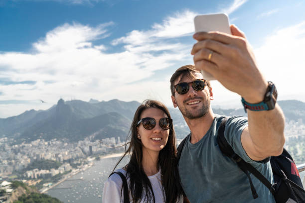 リオデジャネイロで携帯電話を使ってセルフを撮る観光客のカップル - リオデジャネイロ 写真 ストックフォトと画像