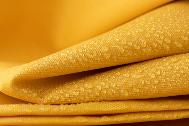 Close-up waterproof and water repellent fabric Close-up waterproof and water repellent fabric.  Water drops on textile. Folded canvas of yellow fabric polyester photos stock pictures, royalty-free photos & images