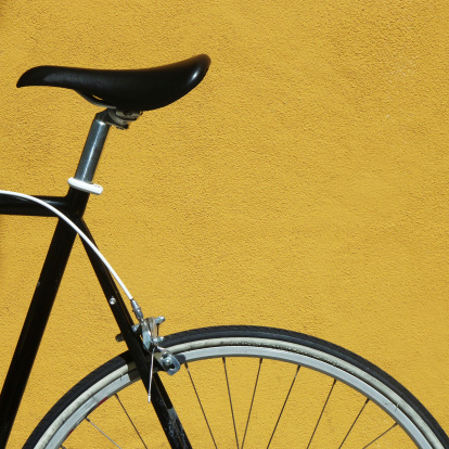 Detail of a black bicycle against a yellow wall