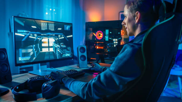 happy gamer playing first-person shooter online video game on his powerful personal computer. room and pc have colorful neon led lights. cozy evening at home. - people joy relaxation concentration imagens e fotografias de stock