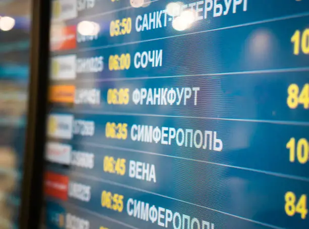 Photo of Electronic scoreboard flights and airlines. Destinations wrote in Russian language translate are: Simferopol, Bahrain, Minsk, St.Petersburg, Sochi, Frankfurt, Vienna. Airport flight information arrival displayed on departure board, flight status changing