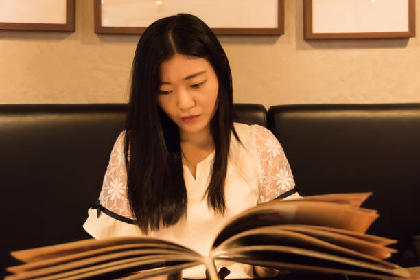 istock Girl reading a book in a western restaurant 1157170597