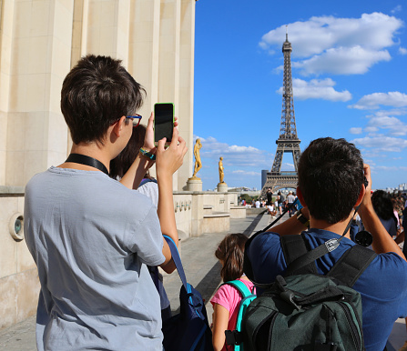 Young caucasian tourists take pictures of Eiffel Tower in Paris France from Trocadero Quartier