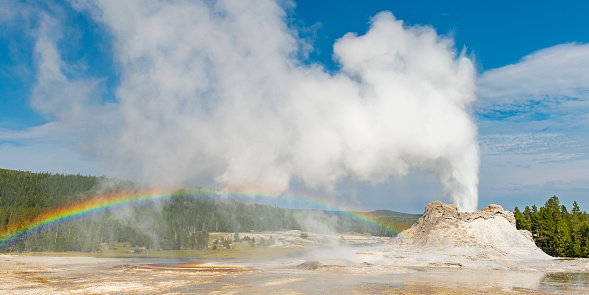 Panoramic photograph of the famous Castle Geyser with eruption and rainbow in the Upper Geyser Basin of Yellowstone national park, Wyoming, United States of America, USA.
