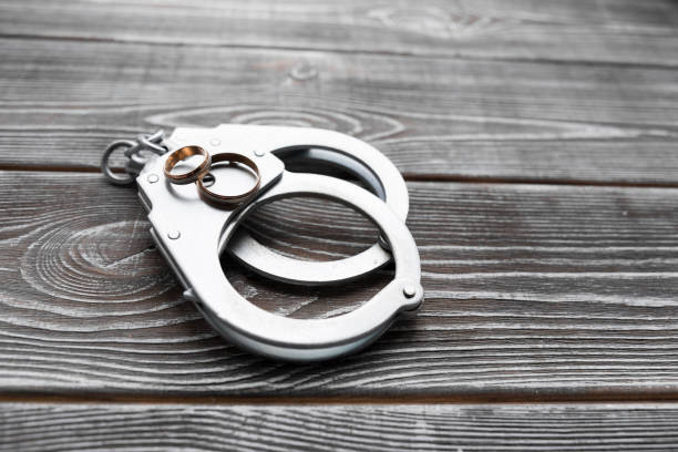 istock handcuffs, wedding rings on a wooden background 1157175033
