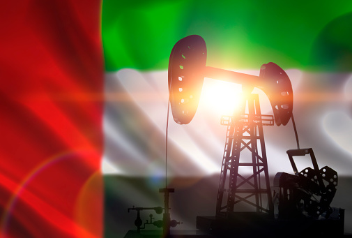 Oil drilling pump on background of flag of Emirates