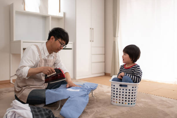 Stay-at-home-father ironing in living room Everyday life of stay-at-home-father with child father housework stock pictures, royalty-free photos & images