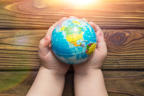 istock globe in hands in the sun on a wooden background 1157175691