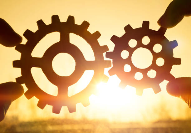 istock Two hands holding gears together. against the sunset. 1157175706