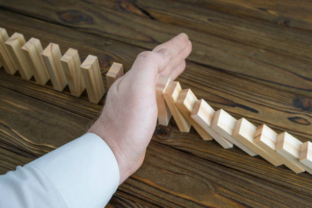 istock a male hand stopping the domino effect. retro style image executive and risk control concept. 1157179705