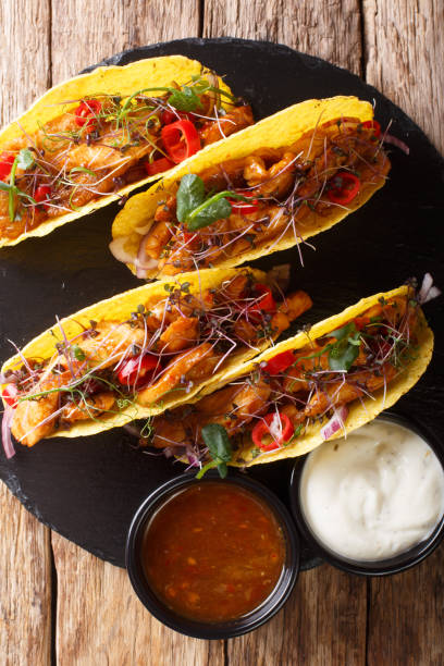 istock Authentic tacos with glazed chicken, microgreen and vegetables are served with sauces close-up. Vertical top view 1157179792