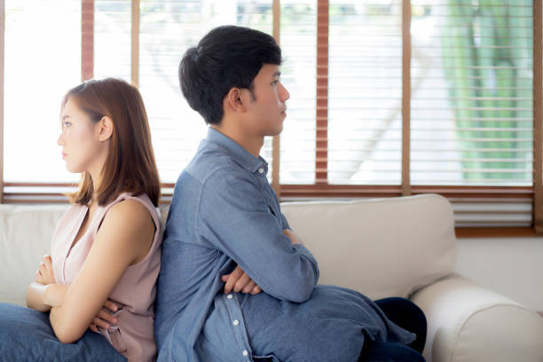 Relationship of young asian couple having problem on sofa in the living room at home, family having conflict argument with unhappy, man and woman with issue, failure and stress together. stock photo