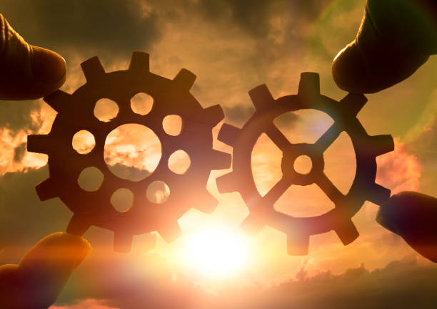 istock Two hands holding gears together. against the sunset. 1157185935