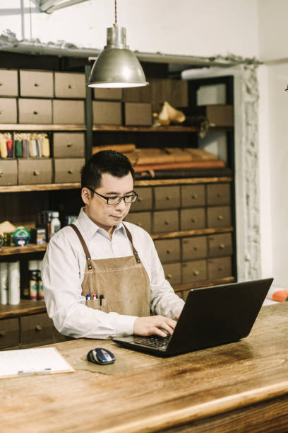 istock Shop Manager working on laptop at table in shoe store 1157189700