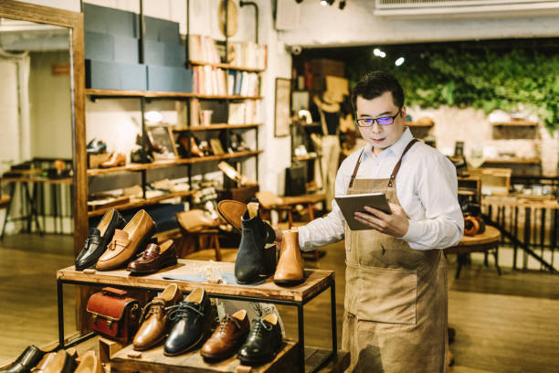 店舗での作業中にデジタルタブレットを使用する所有者 - shoe store shoe shopping retail ストックフォトと画像