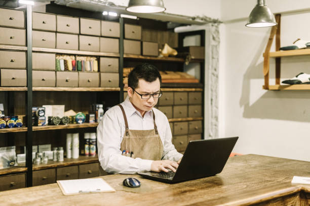 istock Shop Manager working on laptop at table in shoe store 1157189718
