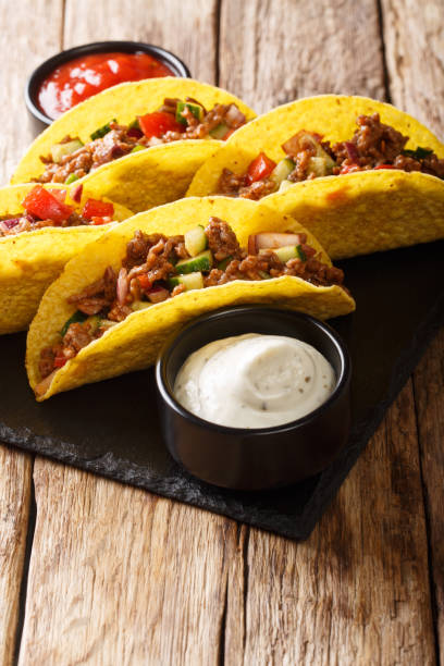 istock Corn tacos filled with minced beef and vegetables served with sauces close-up. vertical 1157190502
