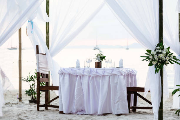 istock White tones. Romantic luxury dinner at tropical beach on sunset. Decorated table with vine glasses 1157191261