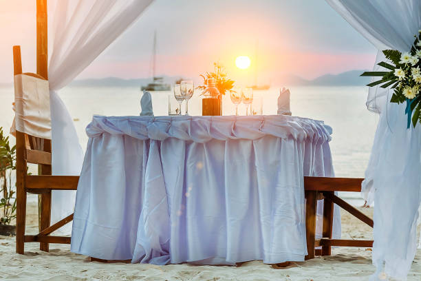 istock Romantic dinner table on the tropical beach, During sunset, ships in the sea on background. 1157191281