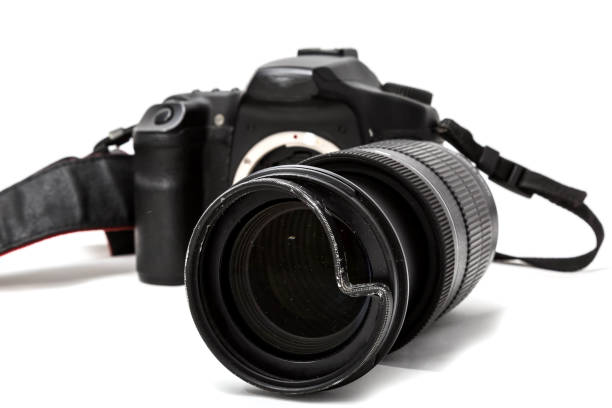 istock Broken digital SLR camera, dented protective filter on the zoom lens. Will be repaired. Isolated on white background. Side view 1157191311
