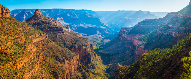 Panoramic vista down the Bright Angel Trail to the green oasis of Indian Garden and the early morning rays of sunlight illuminating the North Rim of the Grand Canyon National Park, Arizona, USA.