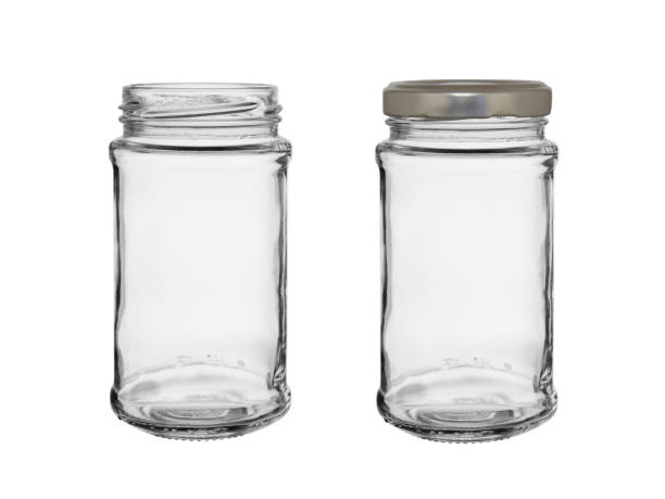 Two empty glass jars isolated on a white background. One is closed by a metal cover.