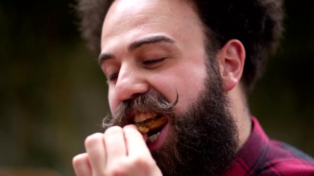 Bearded man enjoying a chicken wing