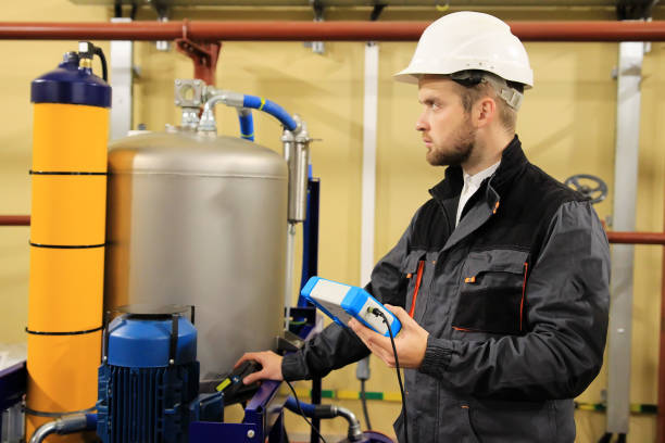 HVAC maintenance engineer checking technical data of heating system equipment in boiler room stock photo