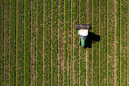 Drone shot of tractor cultivating agricultural field.