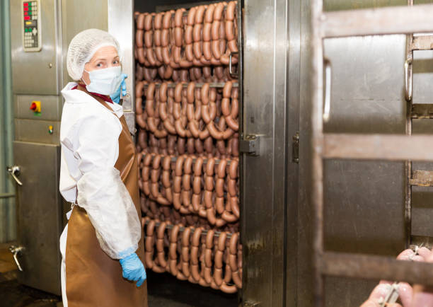 istock Woman checking sausages in baking machine 1157212203