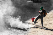 a single male rioter trying to get rid of tear gas bomb