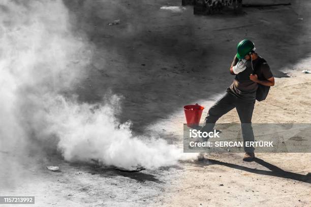 A Single Male Rioter Trying To Get Rid Of Tear Gas Bomb Stock Photo - Download Image Now
