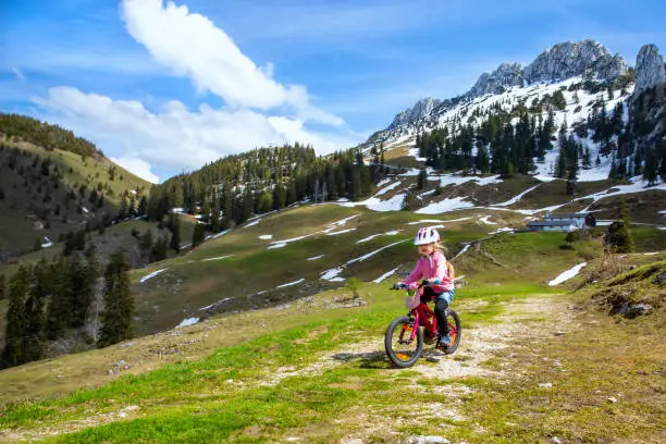 Girl cycles over the alpine meadows of the Kampenwand in chiemgau